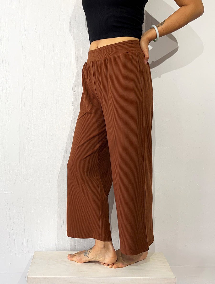 Right quarter view of model wearing simulacra's rib flow pant in the color caramel