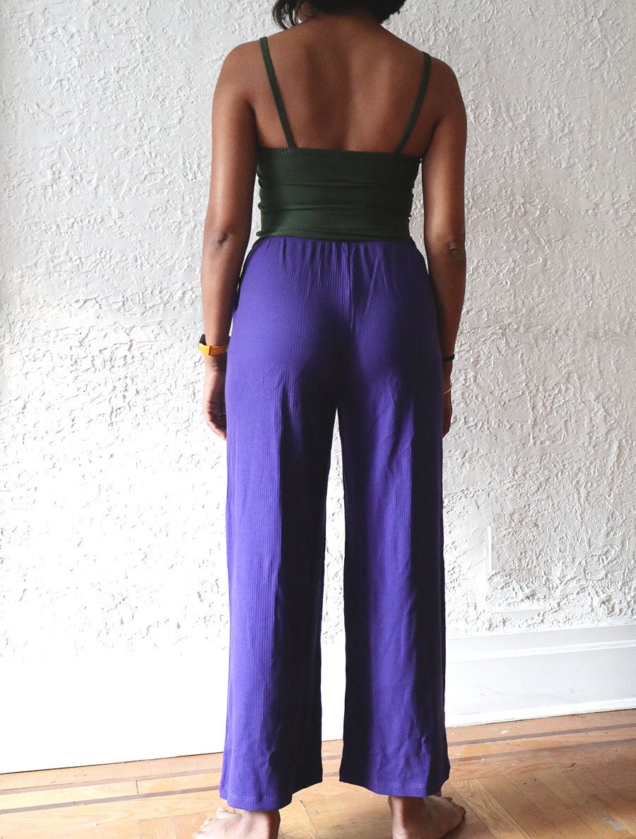 Back view of model wearing simulacra's rib flow pant in the color Iris