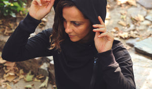 Model walking through a leafy stone path wearing simulacra's black zipped hoodie