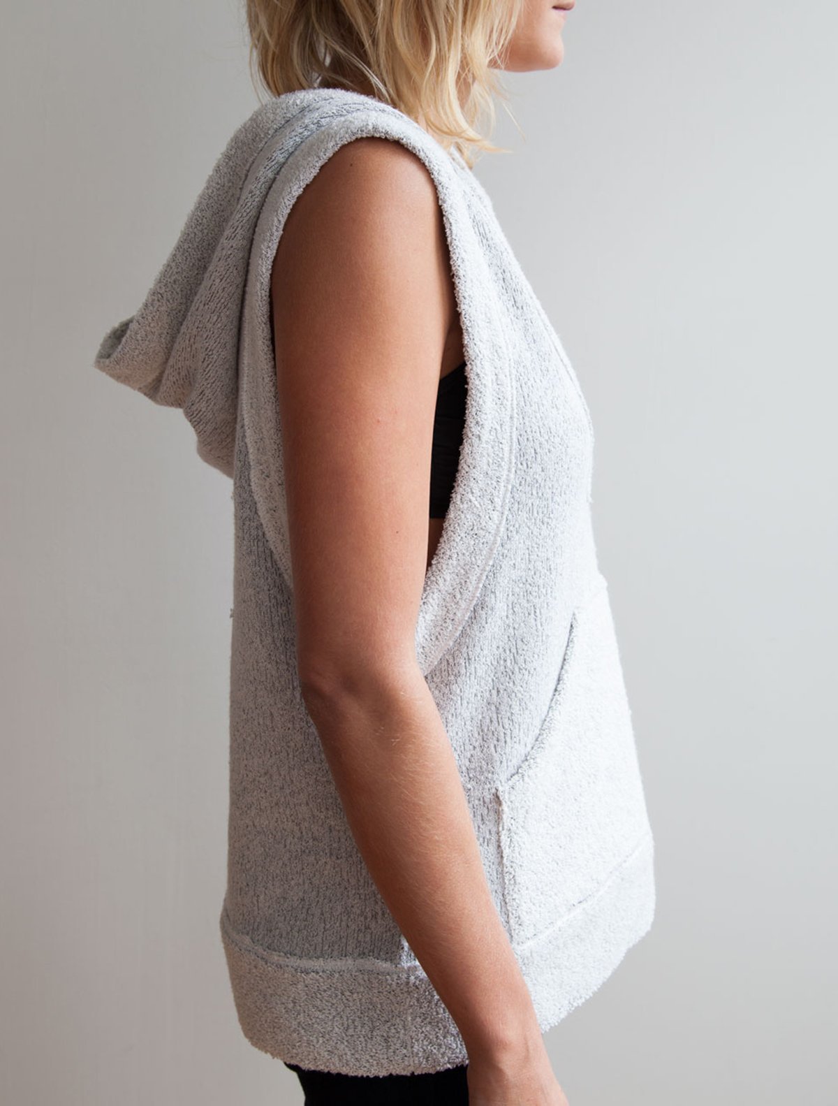 Close up side view of model wearing simulacra's women's sleeveless hoodie