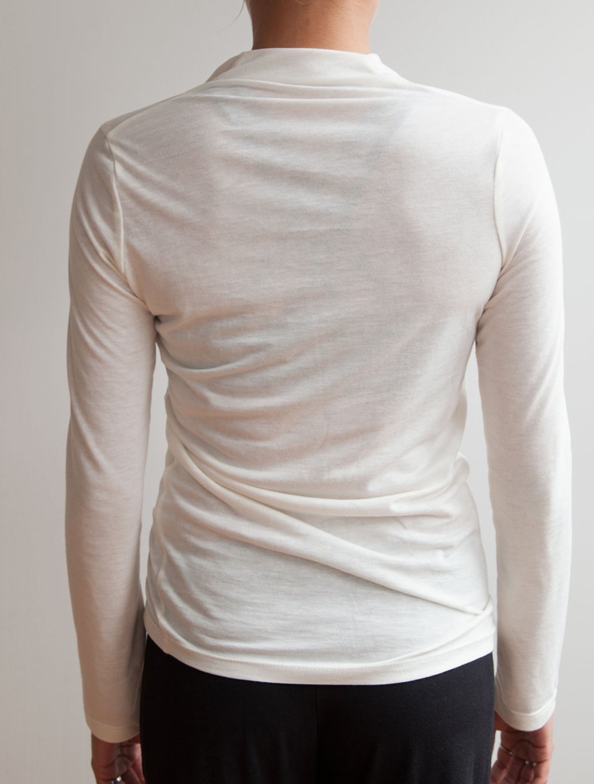back view of model wearing simulacra's white Long Sleeve Twist Top 