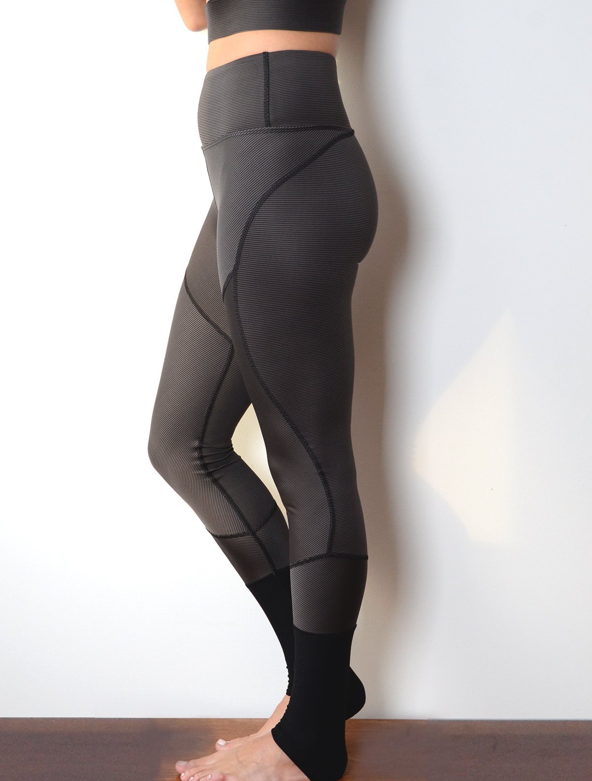 Side view of model wearing simulacra's women's full-length color block leggings in the grey/black stripe