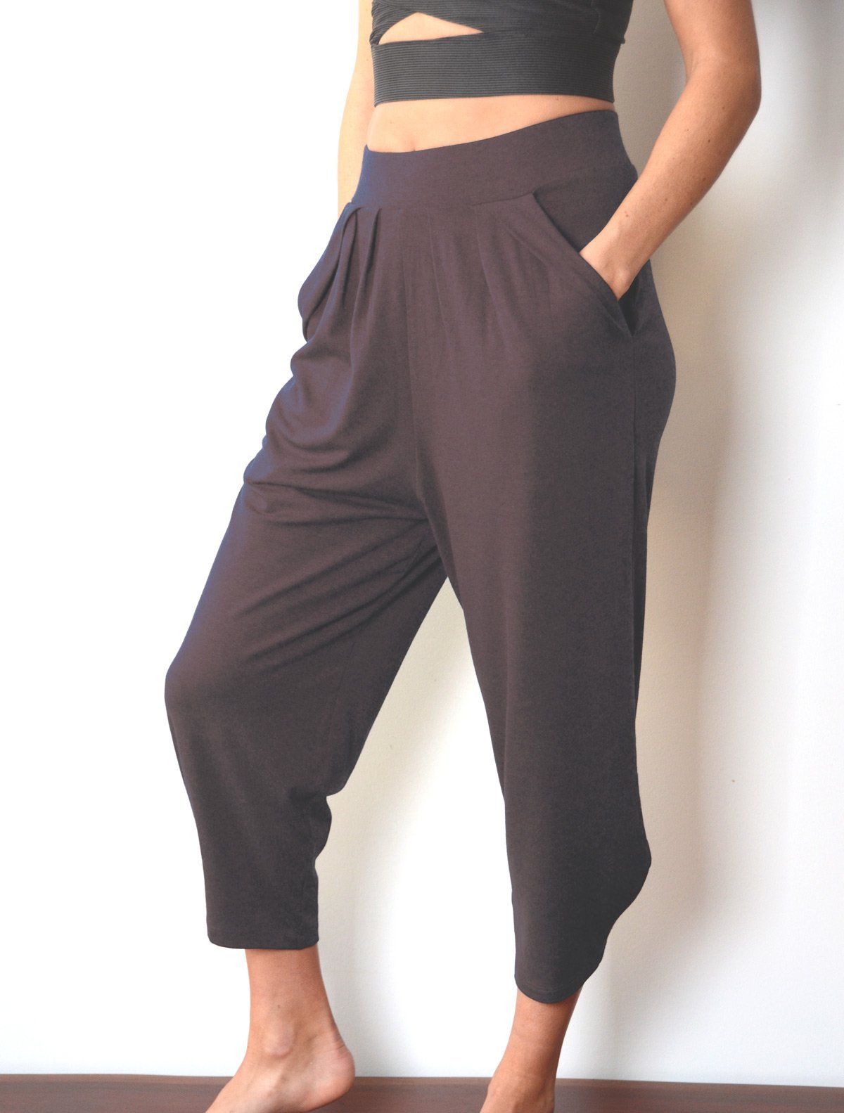 Side view of female model wearing simulacra's pleated drop crotch harem pants in grey
