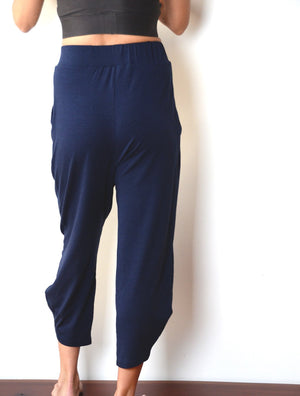 back view of female model wearing simulacra's pleated drop crotch harem pants in blue