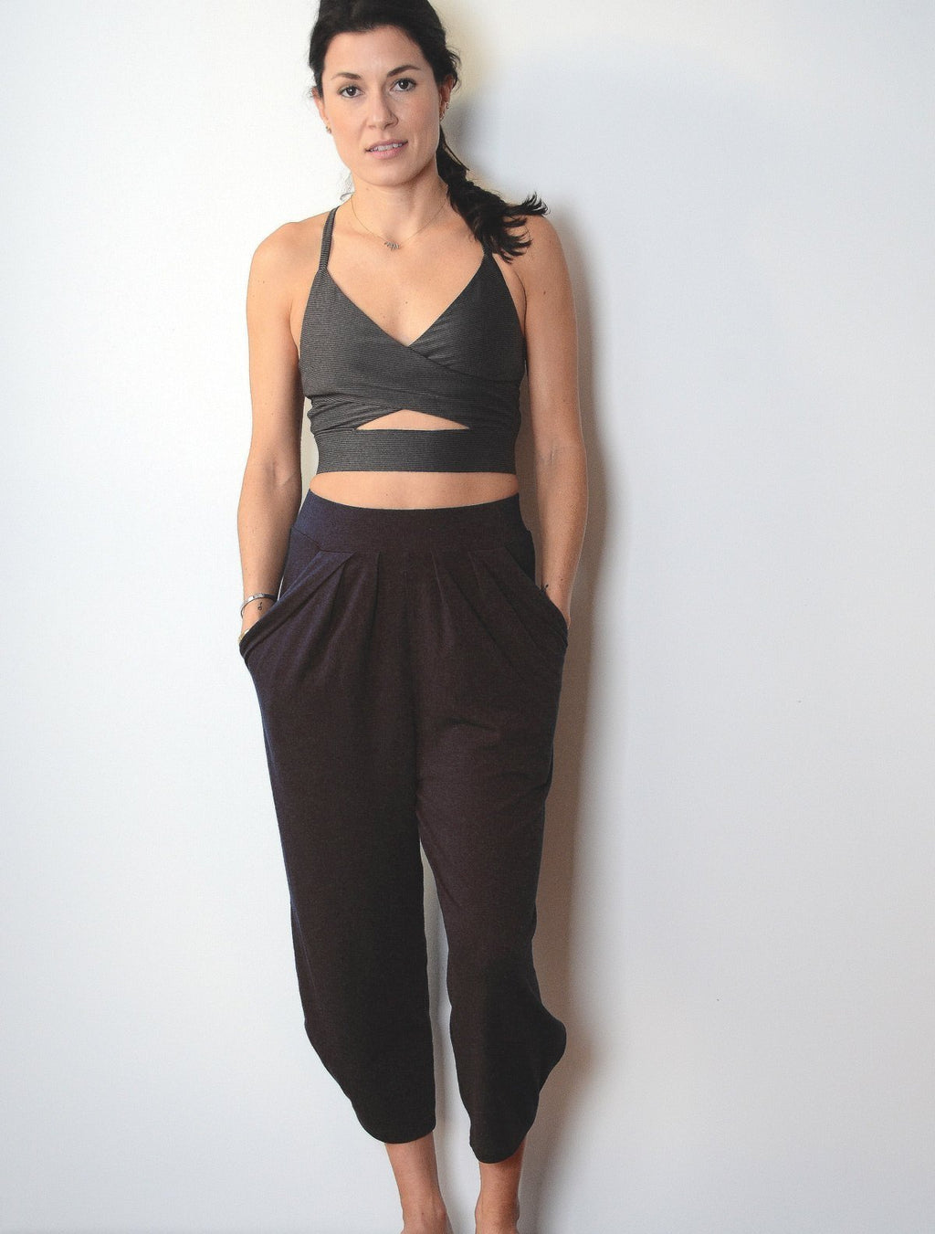 Front view of female model wearing simulacra's pleated drop crotch harem pants in black
