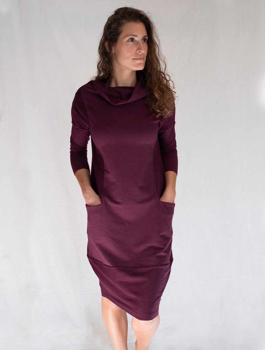 Front view of model wearing simulacra's funnel neckline cocoon dress with pockets, in the color plum