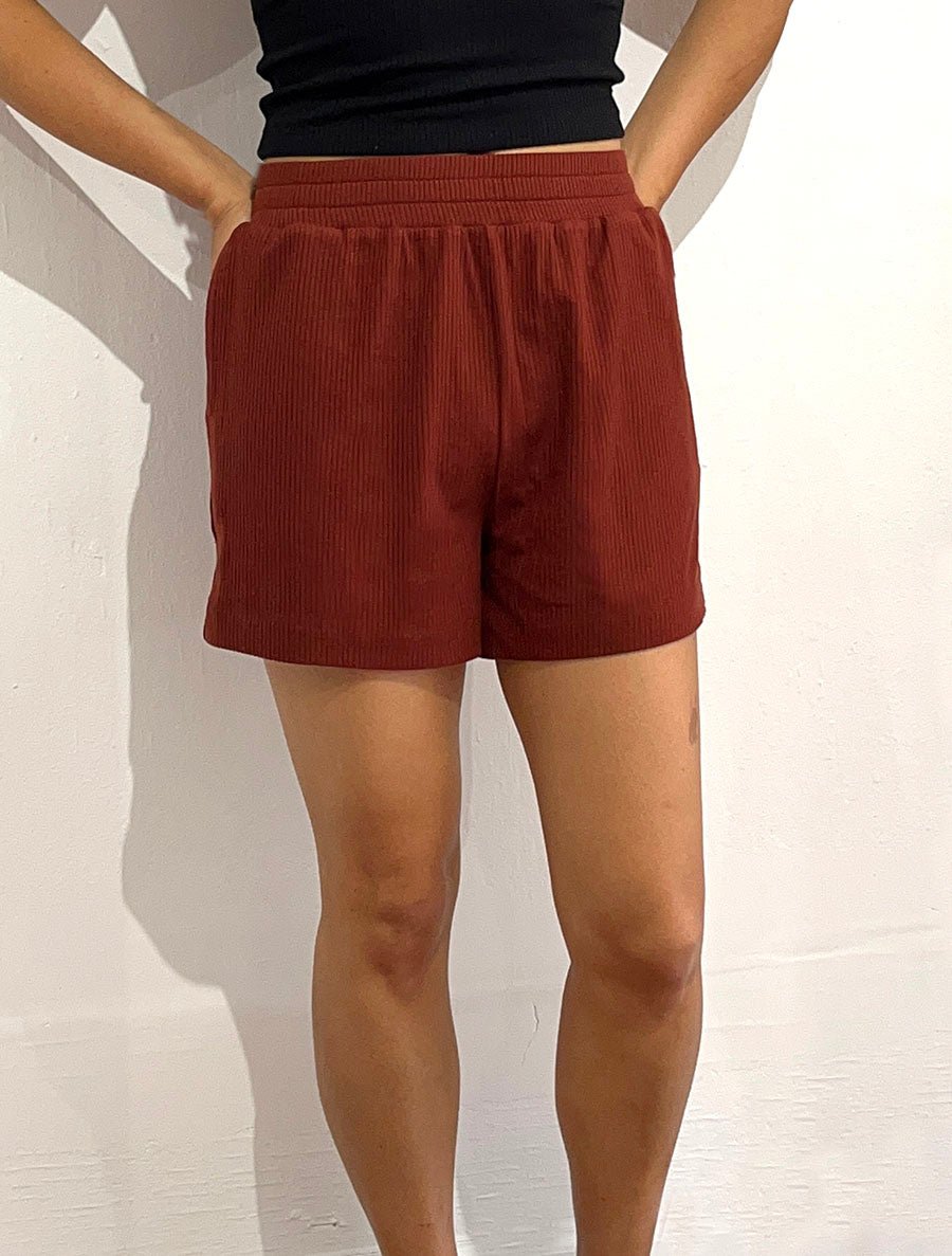 Front view of model wearing simulacra's rib flow short in brick