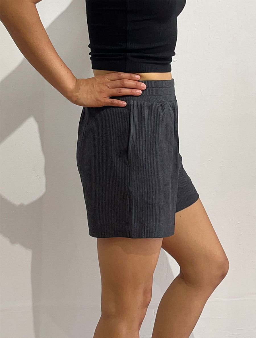 Side view of model wearing simulacra's rib flow short in charcoal