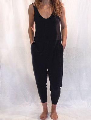 Front pose view of woman wearing simulacra's black sleeveless loose jumpsuit
