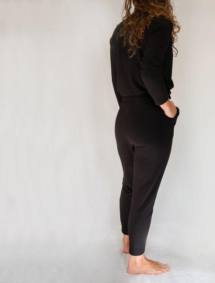 Back/right view of model wearing simulacra's black winter jumpsuit